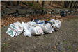 A dozen large bags of trash and some boxes contain trash that has been cleaned up.