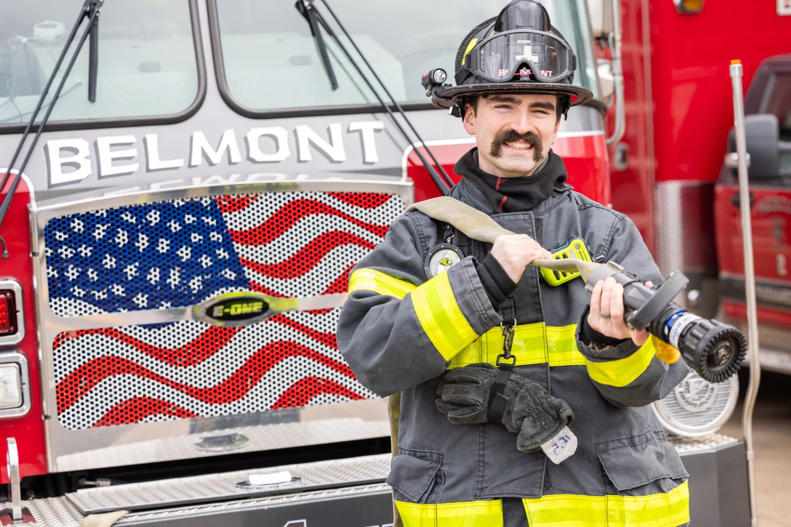 Belmont Firefighter Smiling and Pulling Hose
